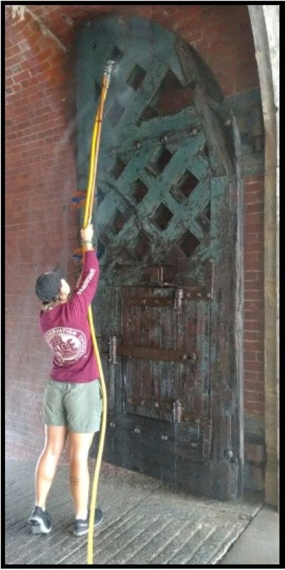Women holding large tool above her head to clean large doors