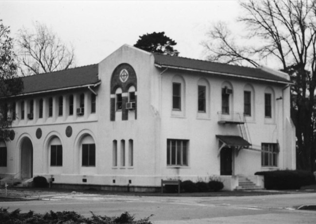 Black and white photograph of a large two-story building in the Mission/Spanish Revival style.