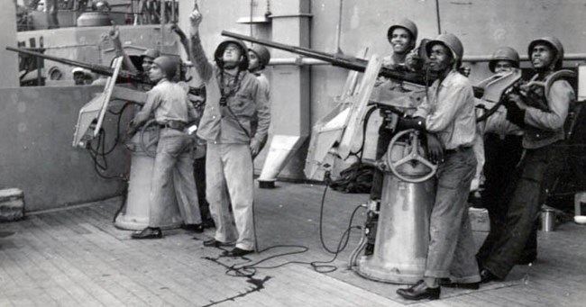 Black Americans gathered for a photo-op to stage them shooting down an enemy plane as they did only seconds before on the USS North Carolina.
