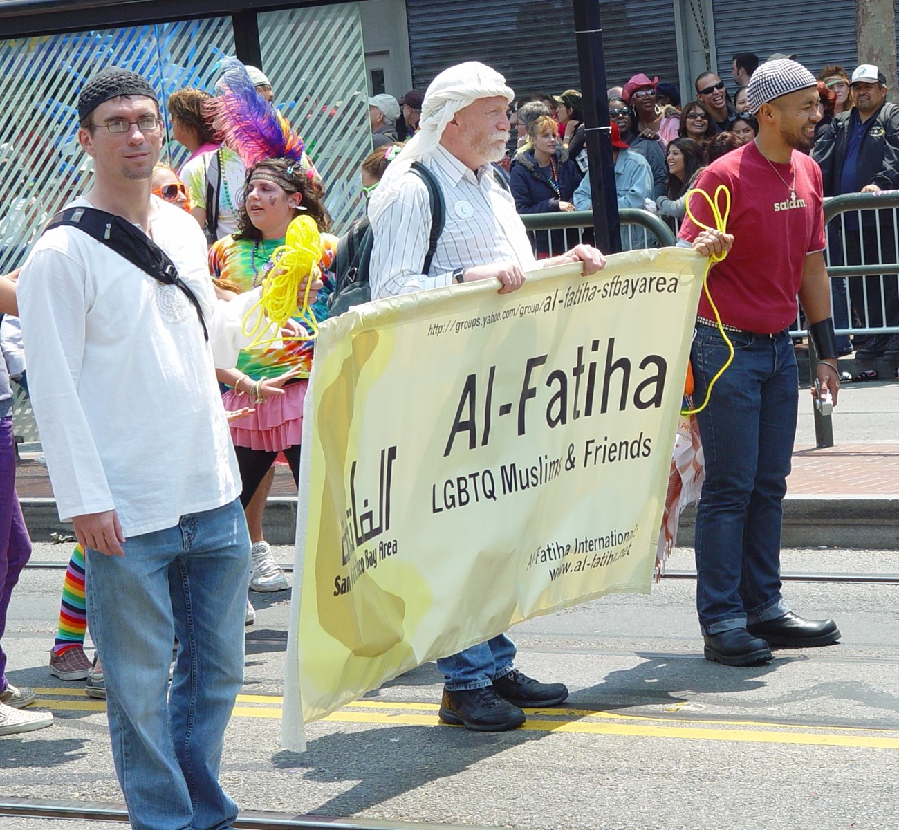 lt= People marching in a Pride Parade. They have a sign that says, "LGBTQ Muslims and Friends."