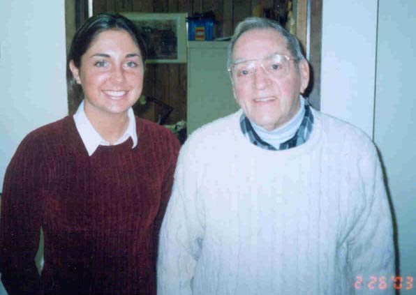 an older man in a sweater stands next to a young woman with brown hair