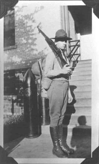 a young man in uniform stands holding a rifle