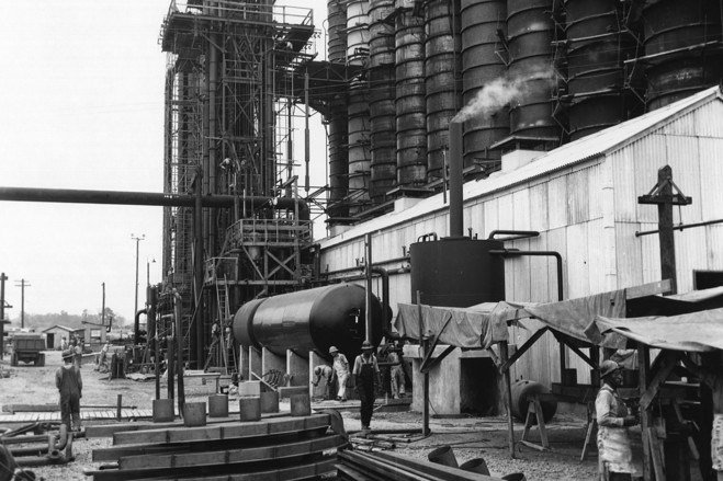 Black and white photo of an industrial building with a few people working.