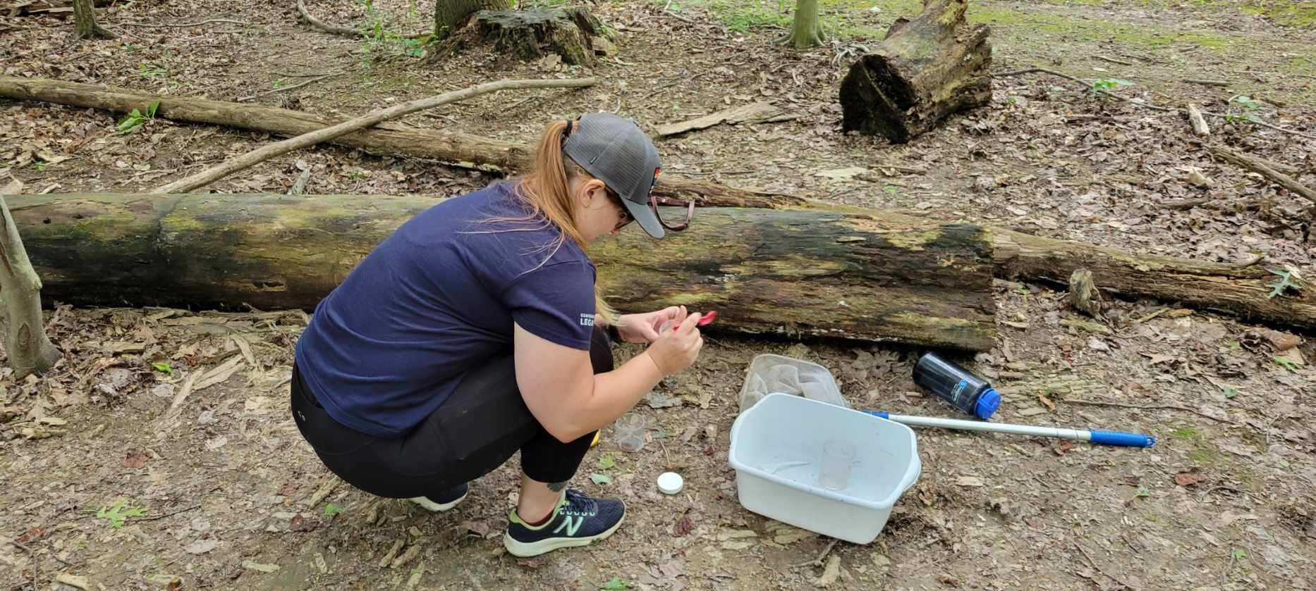 A woman looking at a small organism from a stream.