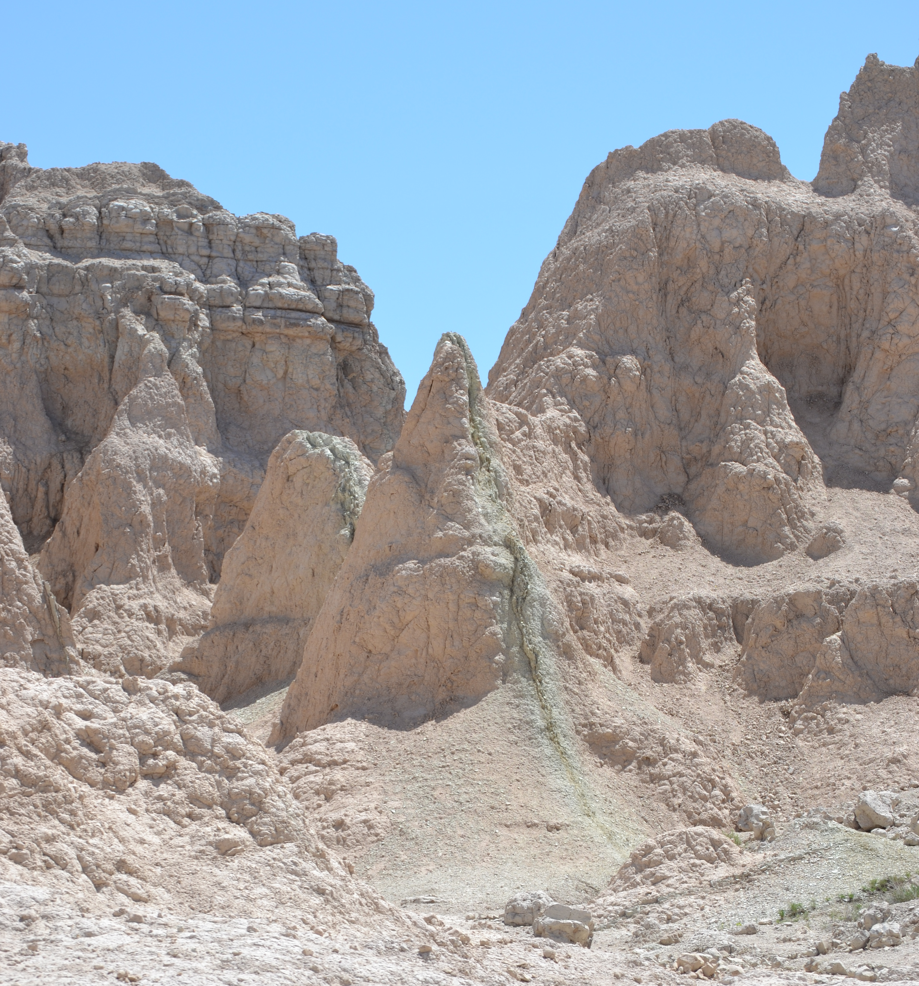 a green line runs vertically through a peak of brown badlands rock