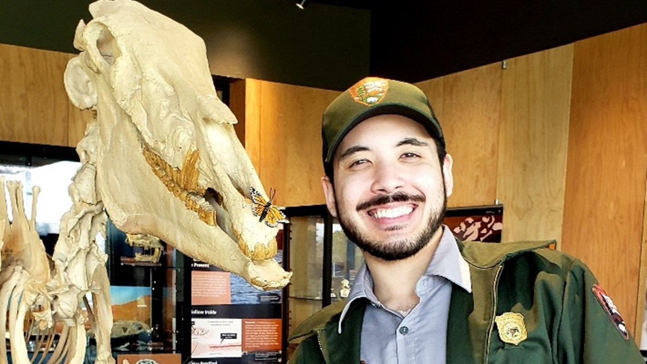 Alexander Kim smiling next to a dinosaur model Alexander Kim smiling next to a dinosaur model
