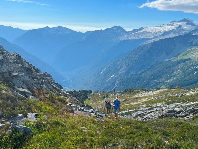 Ameen and his coworker hiking Two individuals hiking in an alpine landscape