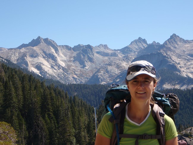 Andi Heard, physical scientist Woman with backpack standing in mountainous landscape.