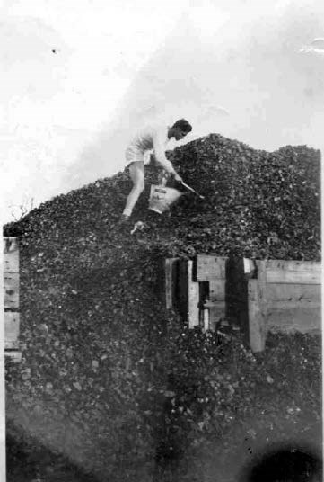 a young mans stands on top of a large black pile of rocks