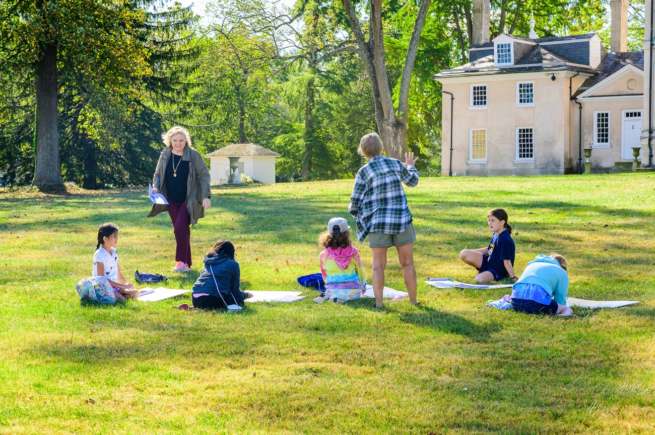 Ann Young visitors listening to Ann speak in front of the mansion