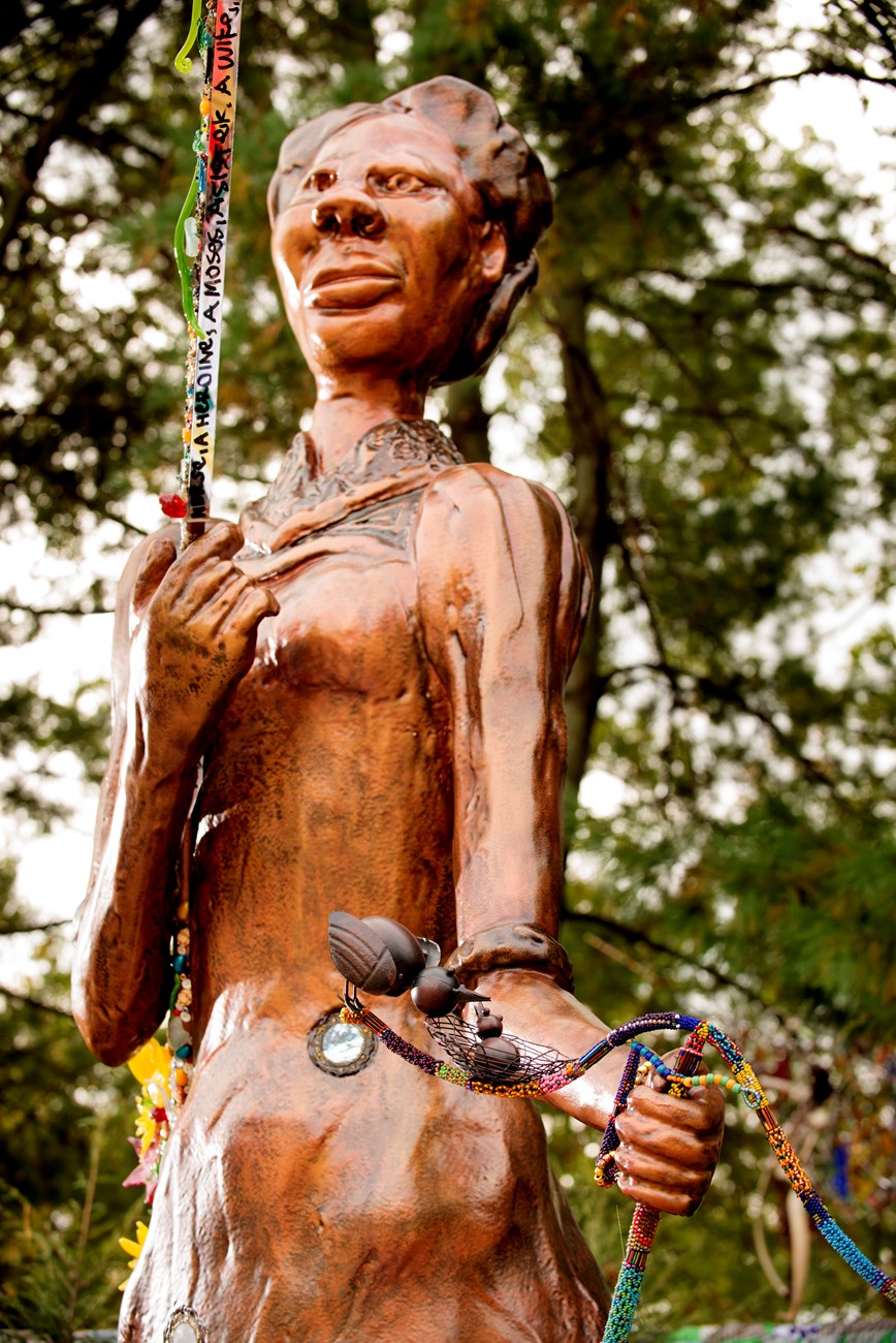 Close up photograph of bronze colored statue of Harriet Tubman facing and standing left.