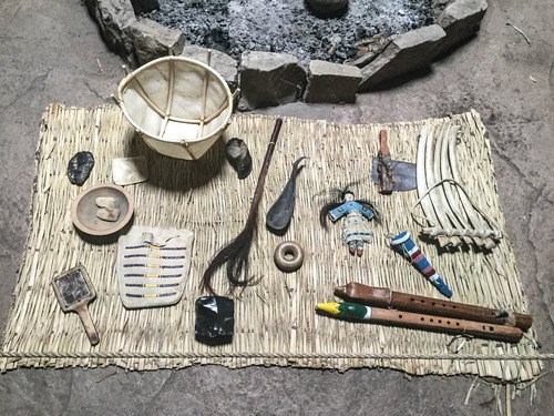 Archeology at Knife River Indian Villages National Historic Site Various Native American supplies on a mat, including a bowl, flutes, bag, doll, brush, and tools at Knife River Indian Villages National Historic Site