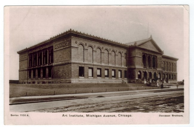 Black and white photo postcard of the exterior of a large building