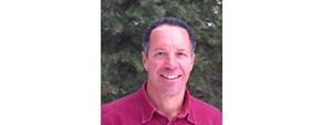 David Thoma Smiling man in red shirt stands in front of green leafy vegetation