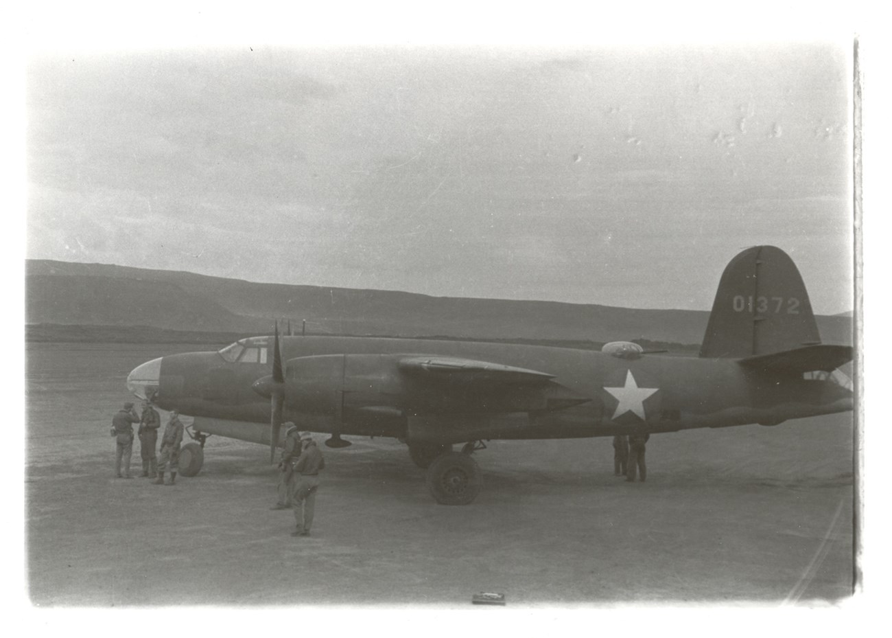 B-26 Tail Number 01372 Side view of a plane with tail number, star on side, and people near the front propellers.