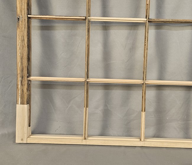 B22Wimg7_dutch A closeup of the bottom right corner of one of the windows. Most of the wood is dark brown and heavily weathered. The bottom rail, the bottom portion of the left stile, and some of the muntin bars have been replaced by newer, brighter tan wood.
