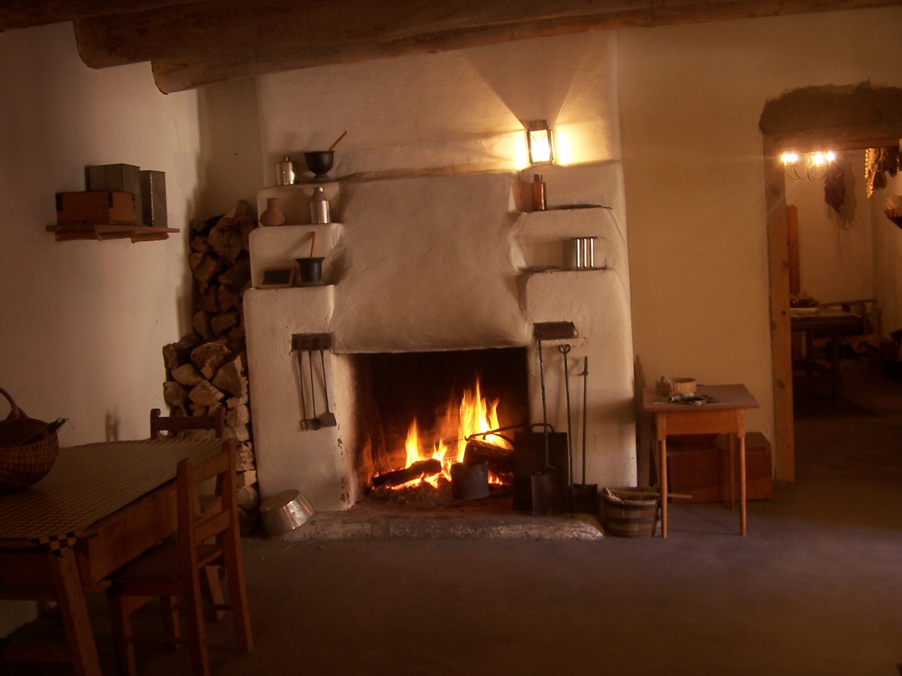 A fire burns in an adobe fireplace, lighting the room.