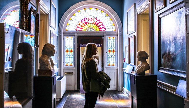 Visitor in a hallway with busts and paintings