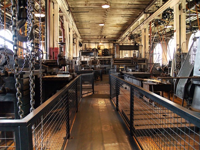 A long hallway with gates on either side protecting various historic machinery.