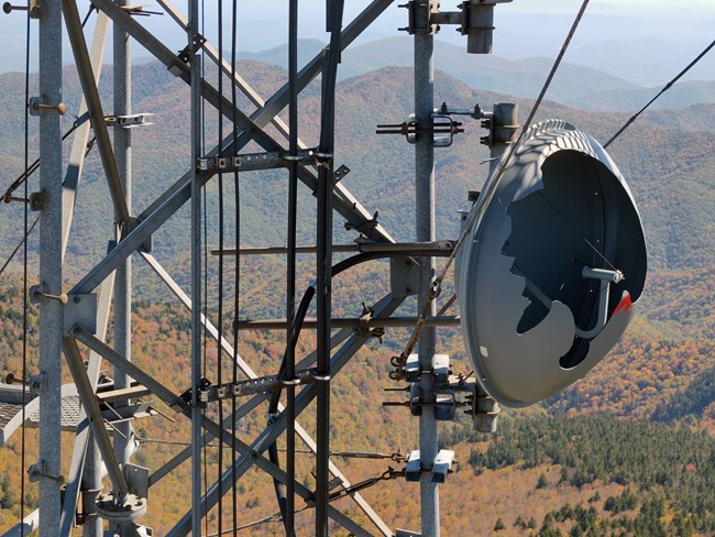 Damage to communication tower. Communication tower with damage against a backdrop of mountains with colorful autumn trees.