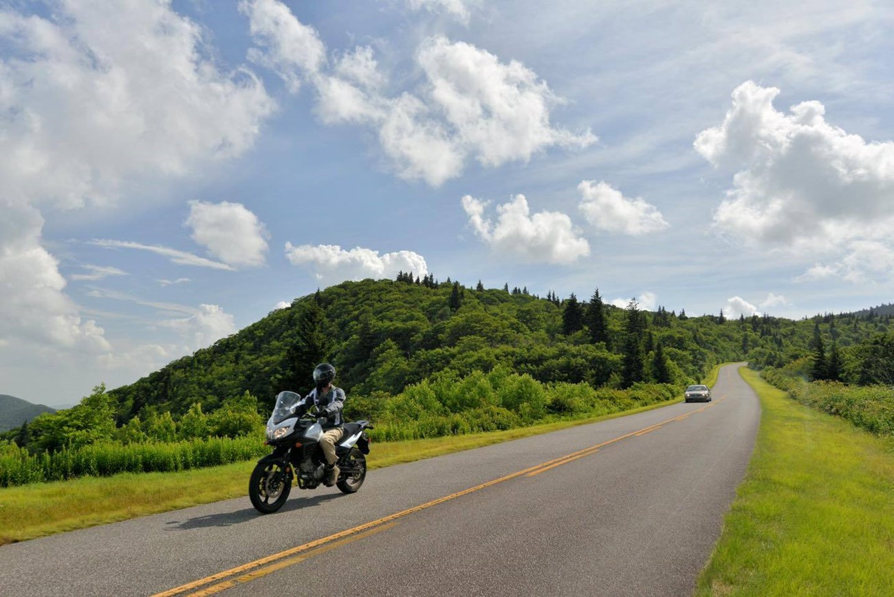Motorcyclist wearing safety gear while traveling on a road in a rural area