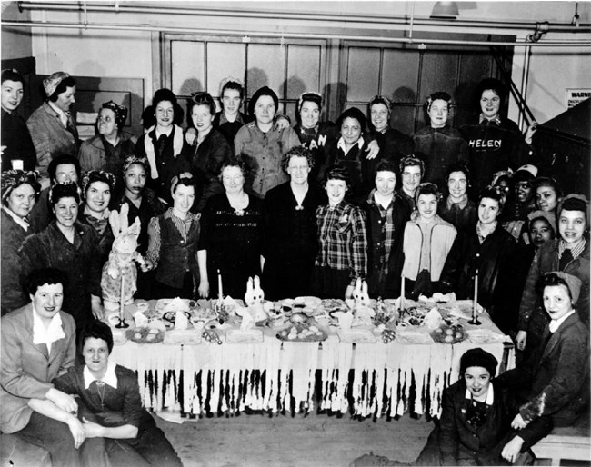 Women workers standing around a table for an Easter party.