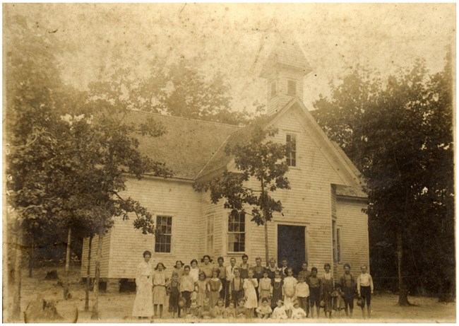 White children standing outside a schoolhouse