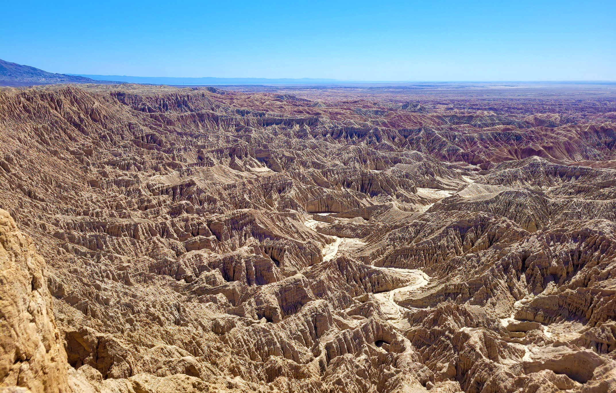 Photo of an irregular landscape with deep troughs and ridges in different colors, blue skies, no visible vegetation