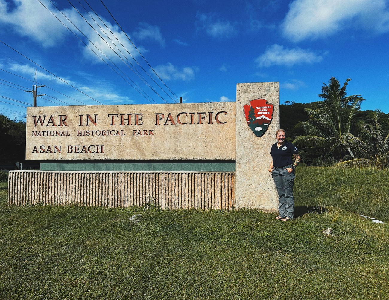 Baylee Bales-Woods, standing in front of the War in the Pacific National Historical Park Asan Beach Units National Park Sign