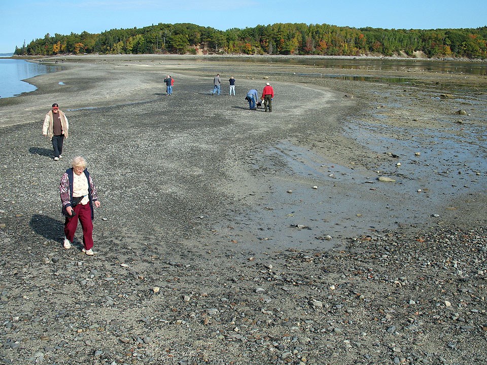 sand and gravel land bridge with people walking across