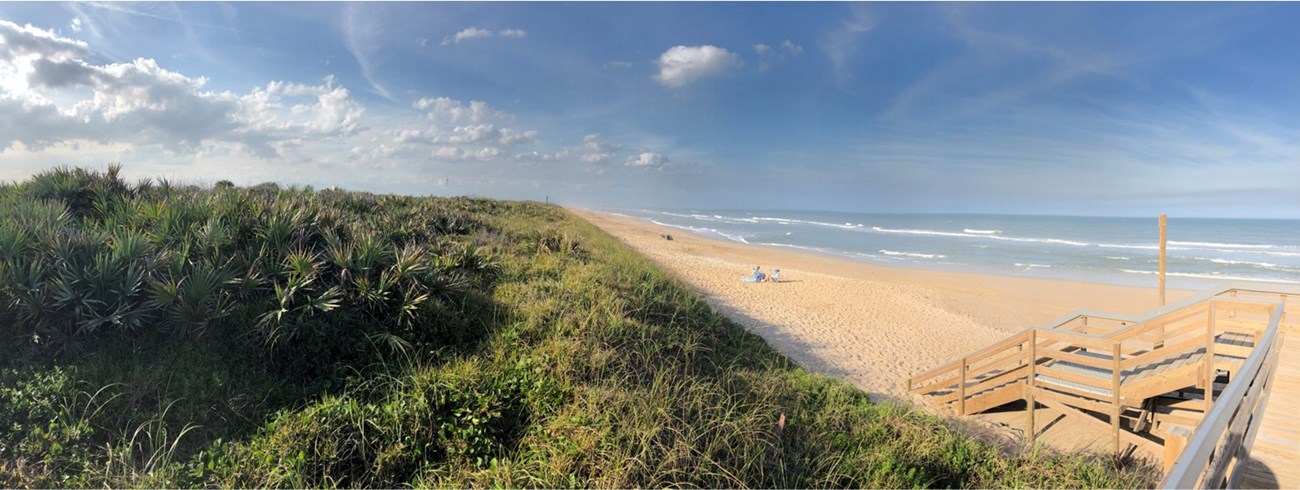 Canaveral National Seashore's dune ridge, the beach, visitors under an umbrella and the Atlantic Ocean. Beach