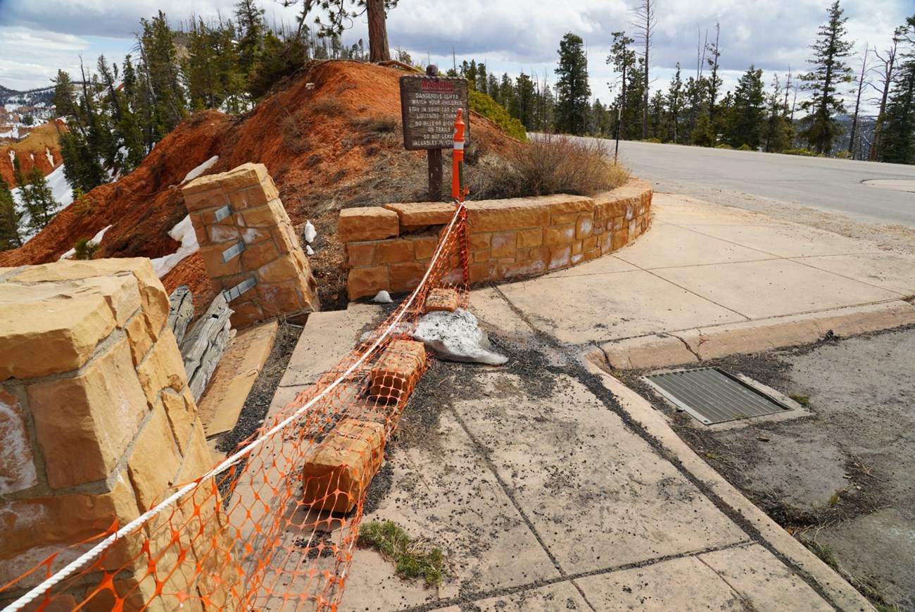 Before Repair A slumping sidewalk beside collapsing fence columns and orange safety fencing
