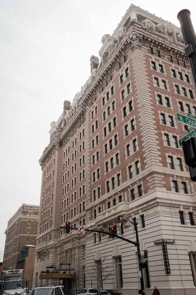 Belvedere Hotel Street corner view of eleven-story tan brick building with stone base and elaborate details near the roofline