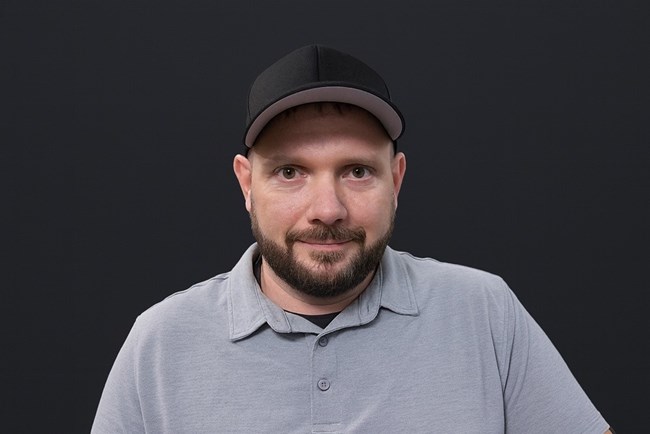 BenSplittstoser a man wearing a black ball cap and gray polo style shirt smiles for the camera