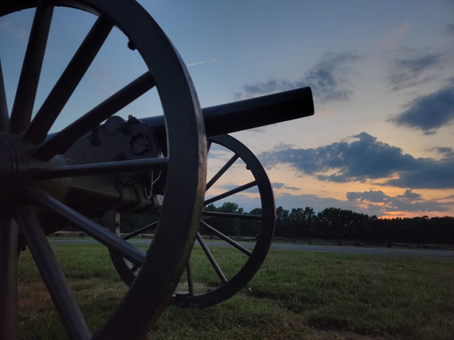 Bentonville Battlefield photo 4 Morning light peaks through clouds over field viewed from ground level, closeup of cannon in foreground and overhead.