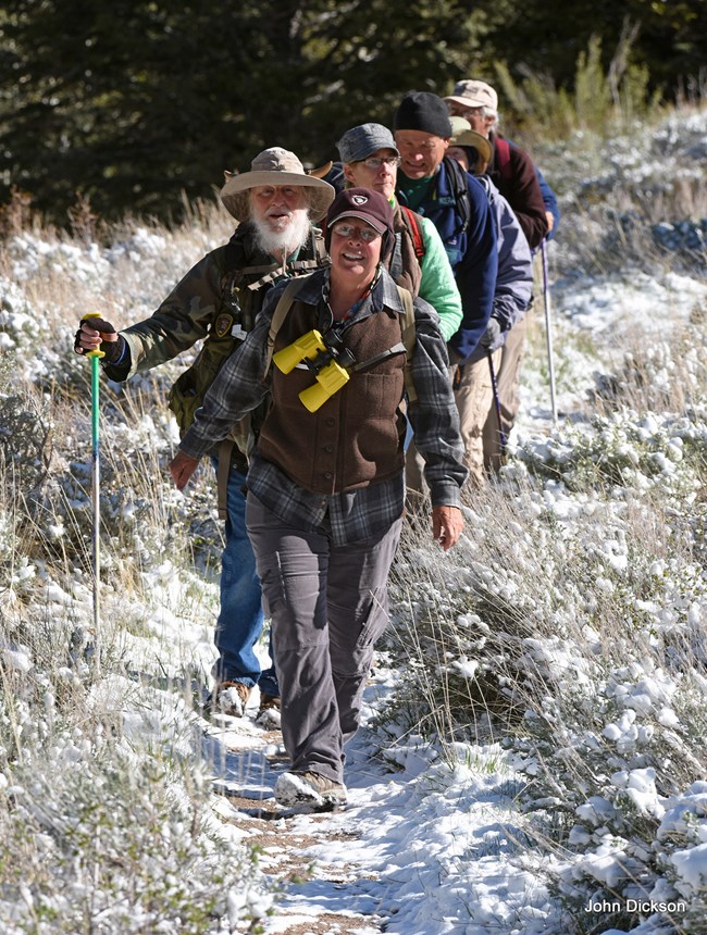 Birders Six bioblitz participants going on a guided hike in a grassy field