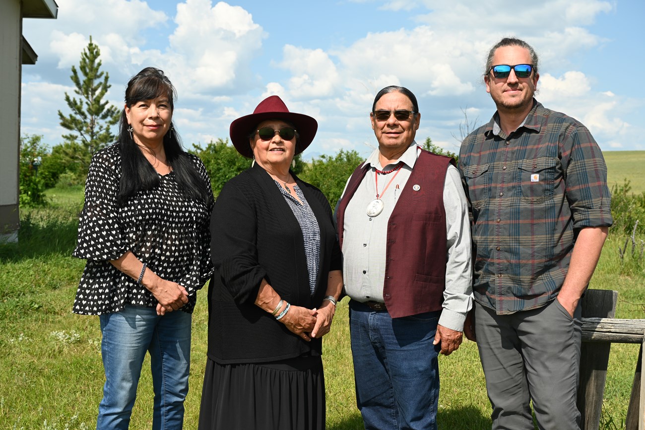 Four people stand in front of a blue sky