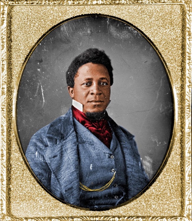 Colorized photo of an African American man in the 1850s wearing a suit and bow tie with large collar.