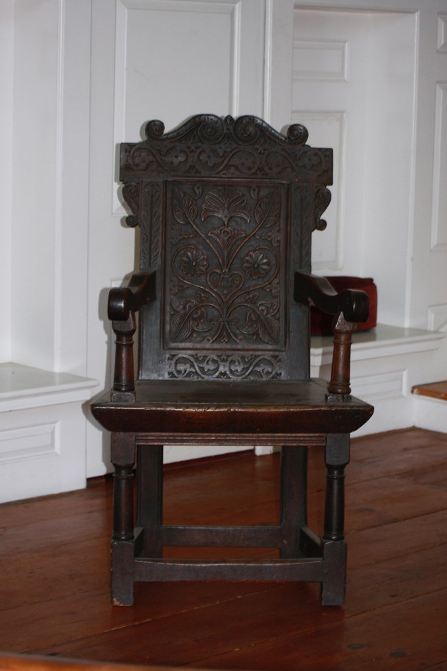Wooden chair, with two arms, on wood floor