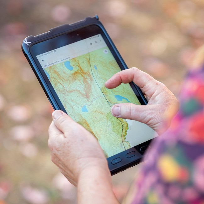 Karen using a tablet with field mapping software displaying a map during GNSS data collection. Tablet showcasing a park map that Karen made.