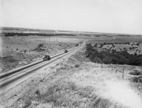 Historic black and white image of a two lane highway.
