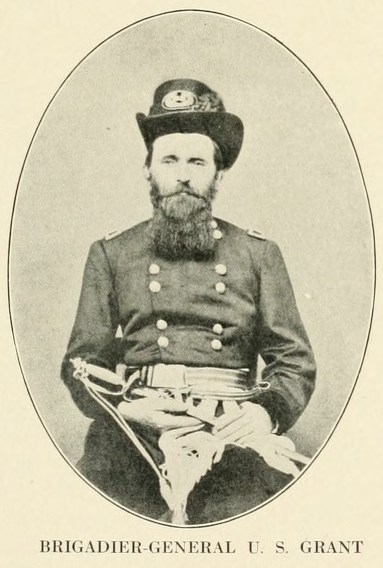 Brigadier General U.S. Grant, 1861 Black and white image of US Grant with a beard and hate facing the camera while on a stool in civil war uniform, text below