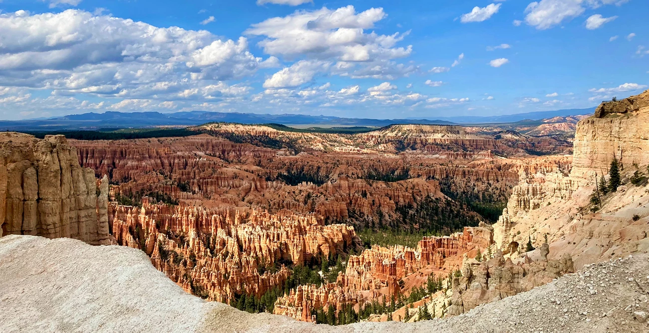 Bryce Canyon's many hoodoos A vast landscape of irregularly shaped, orange and cream-colored rock formations under a blue sky with clouds.