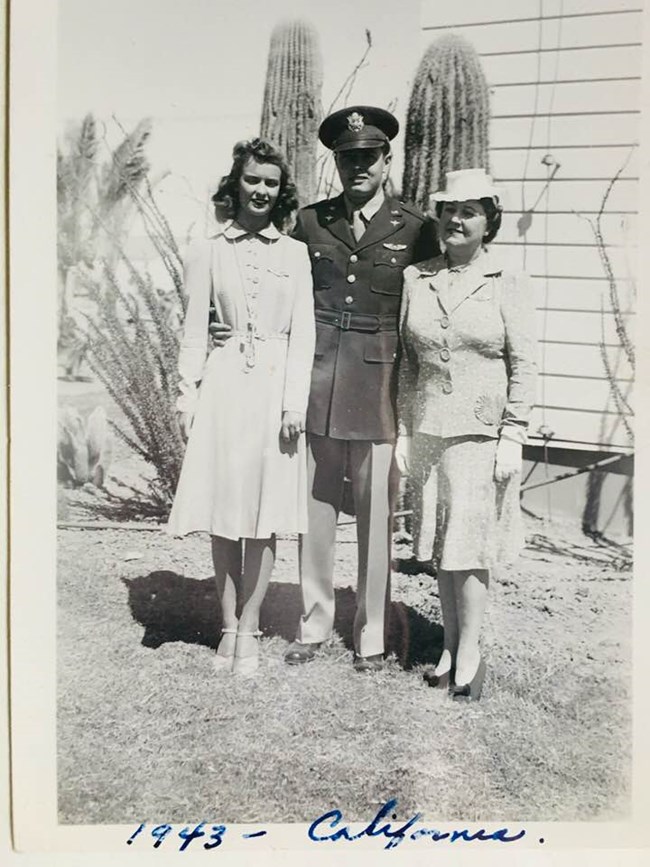 Courtesy of Robin Fleming, granddaughter of A.W. Johnson Black and white photo of a white woman in a dress, a white man in military uniform, and an older woman in a skirt set and hat in front of two cacti