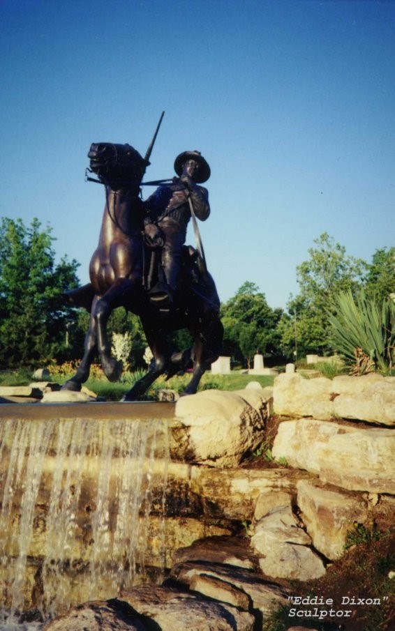 Bronze sculpture of soldier on a horse next to a stone fountain