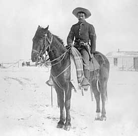 Buffalo_Soldier_(UofAZ) A soldier sits on a horse, an old photo, it is black and white
