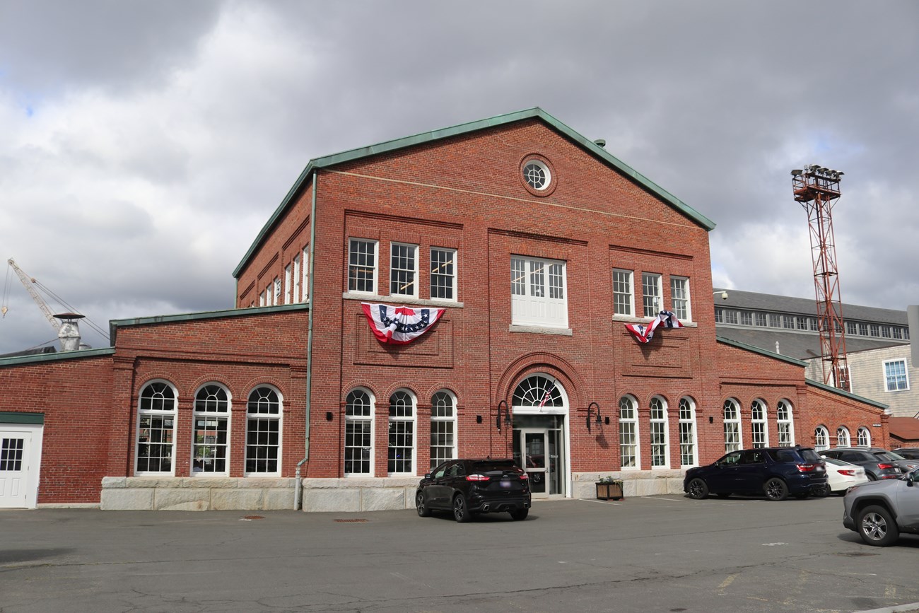 a brick building with a central three-story structure and two one-story wings on either side.