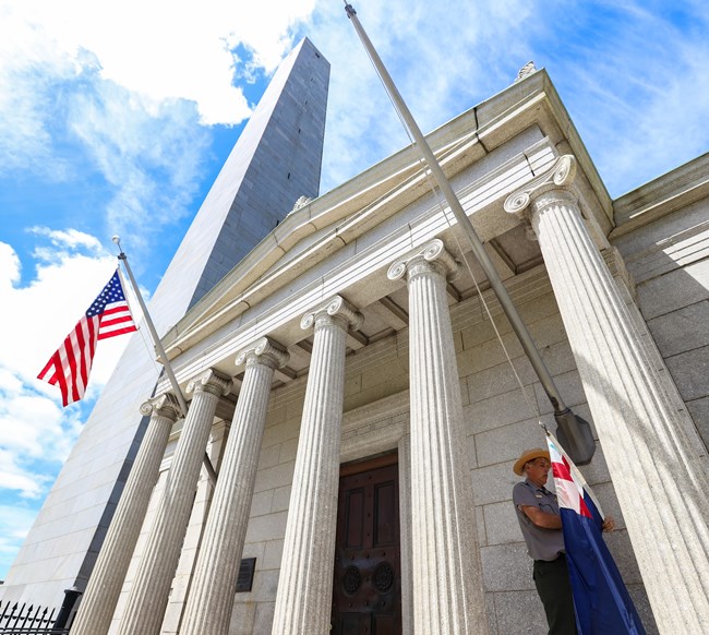 View up the facade of the Bunker Hill Lodge with the blue sky and Monument in the background.