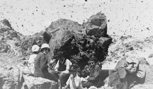 A group of people eat lunch on a rocky summit with a "cloud" of butterflies above them.