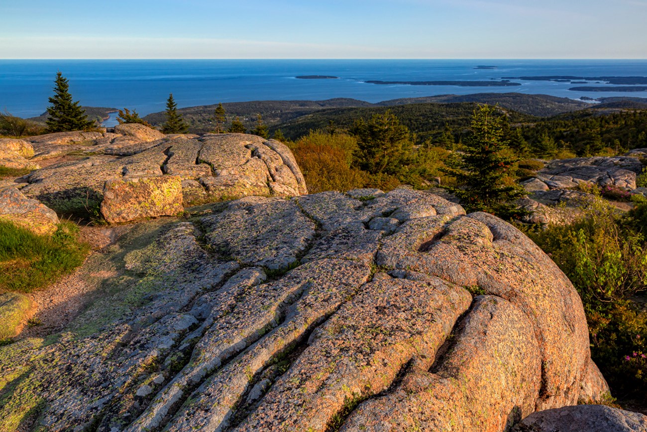 Landscape photo with pink granite boulders in foreground and open ocean with islands in distance Landscape photo with pink granite boulders in foreground and open ocean with islands in distance